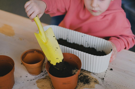 A child planting seedlings with a trowel during a MEC Lifestyle education program